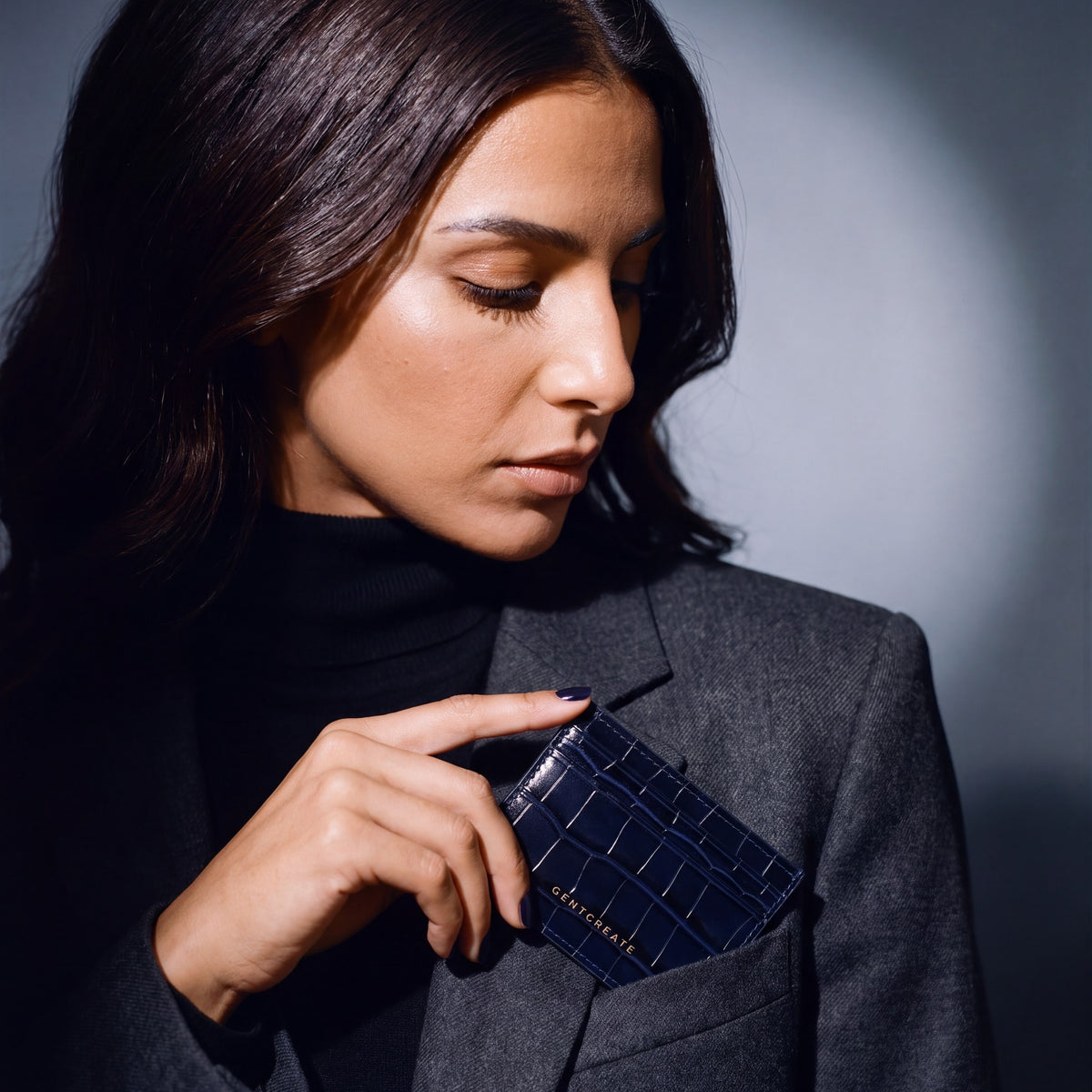 Woman slipping a navy crocodile-embossed leather card holder by GENTCREATE into a blazer chest pocket