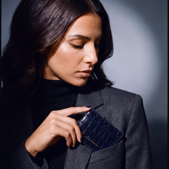 Woman slipping a navy crocodile-embossed leather card holder by GENTCREATE into a blazer chest pocket