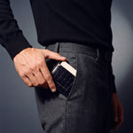 Man sliding a navy crocodile-embossed leather card holder by GENTCREATE into his trouser front pocket