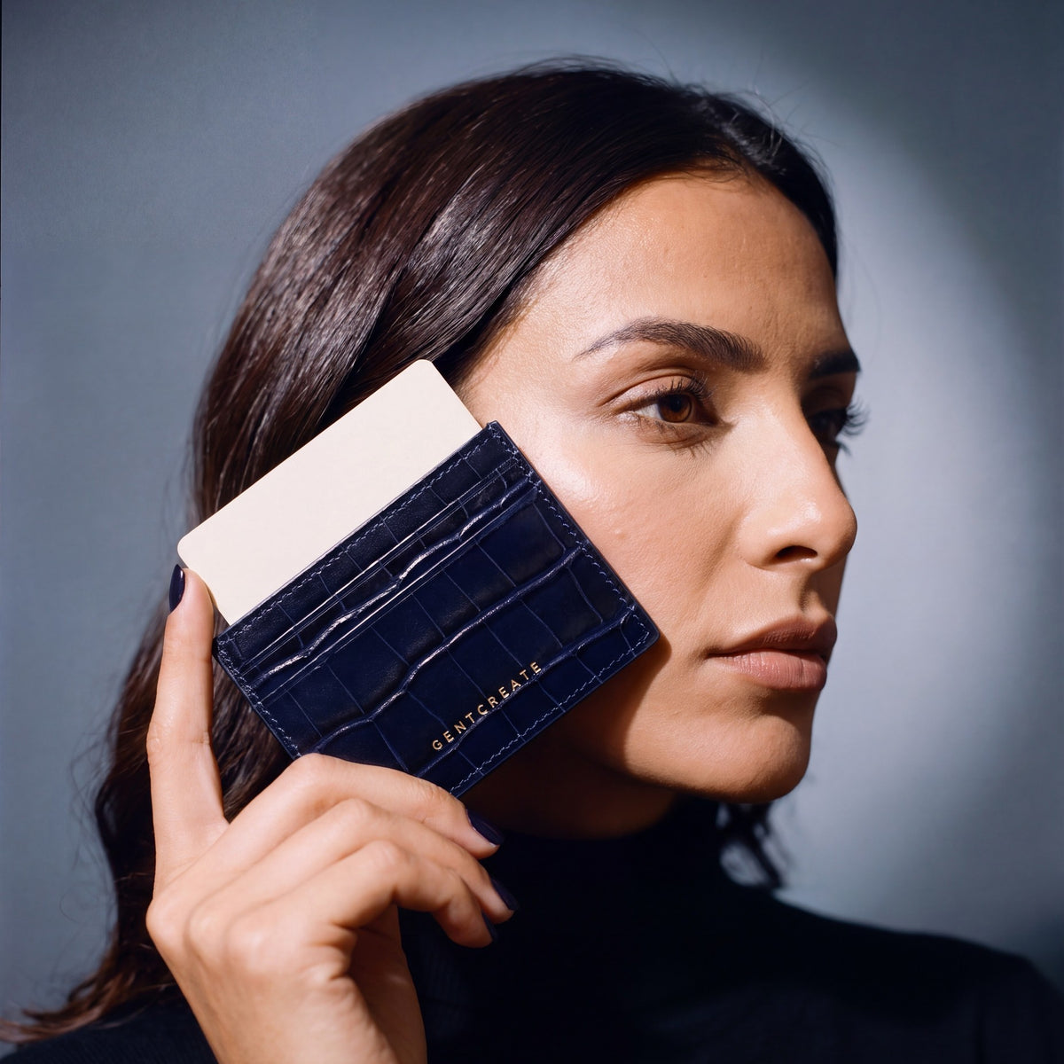 Woman holding a slim navy crocodile-embossed leather card holder by GENTCREATE and drawing out a card