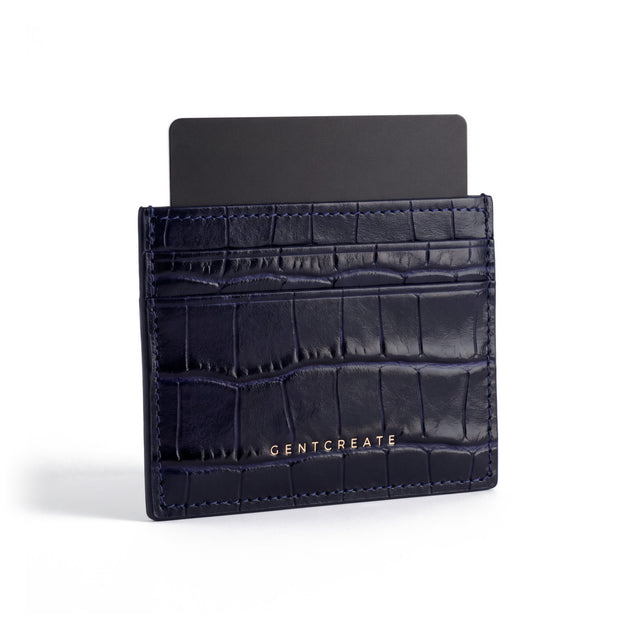 Navy crocodile-embossed leather card holder by GENTCREATE standing with a card, on white