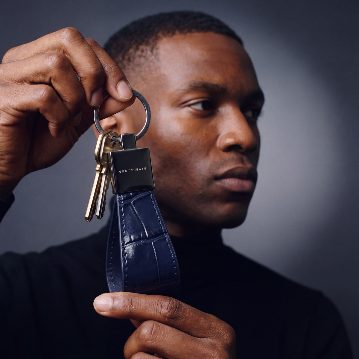 Man holding up a navy crocodile-embossed leather keychain by GENTCREATE with house keys