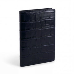 Closed navy crocodile-embossed leather passport holder by GENTCREATE standing on white