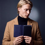 Man opening a navy crocodile-embossed leather passport holder by GENTCREATE with a passport inside