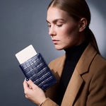 Woman holding a navy crocodile-embossed leather passport holder by GENTCREATE with a blank card tucked in