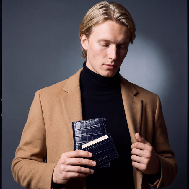 Man holding a matching navy crocodile-embossed leather passport holder and card holder set by GENTCREATE