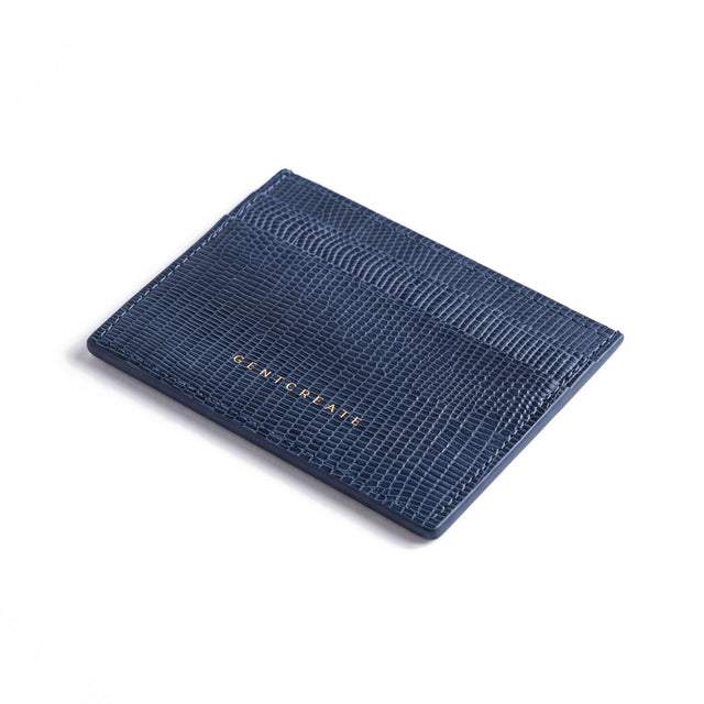 Navy lizard-embossed leather card holder by GENTCREATE lying at an angle on white