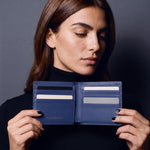 Woman opening a navy lizard-embossed leather bifold wallet by GENTCREATE to show the card slots