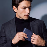 Man sliding a navy lizard-embossed leather bifold wallet by GENTCREATE into a blazer pocket