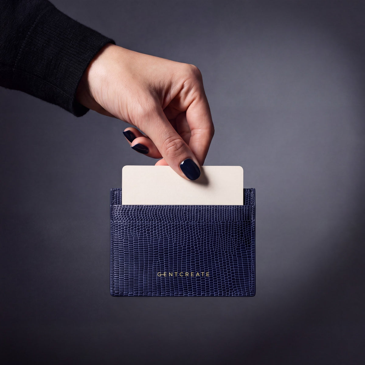 Hand steckt eine Karte in ein marineblaues Kartenetui aus Leder mit Eidechsenprägung von GENTCREATE