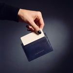 Hand holding a navy lizard-embossed leather card holder by GENTCREATE, a card rising from the top slot
