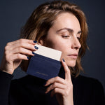 Woman holding a slim navy lizard-embossed leather card holder by GENTCREATE and drawing out a card