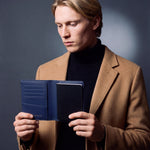 Man opening a navy lizard-embossed leather passport holder by GENTCREATE with a passport inside
