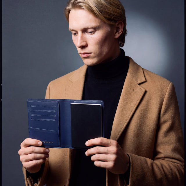 Man opening a navy lizard leather passport holder by GENTCREATE with a passport inside