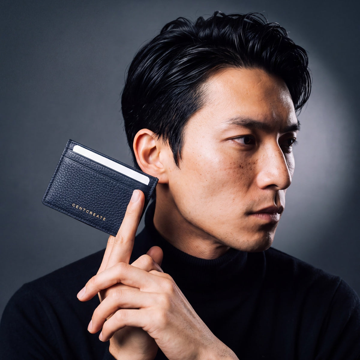 Man holding a slim navy pebble leather card holder by GENTCREATE between two fingers