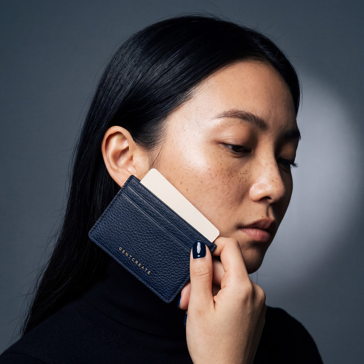 Woman holding a slim navy pebble leather card holder by GENTCREATE and drawing out a card
