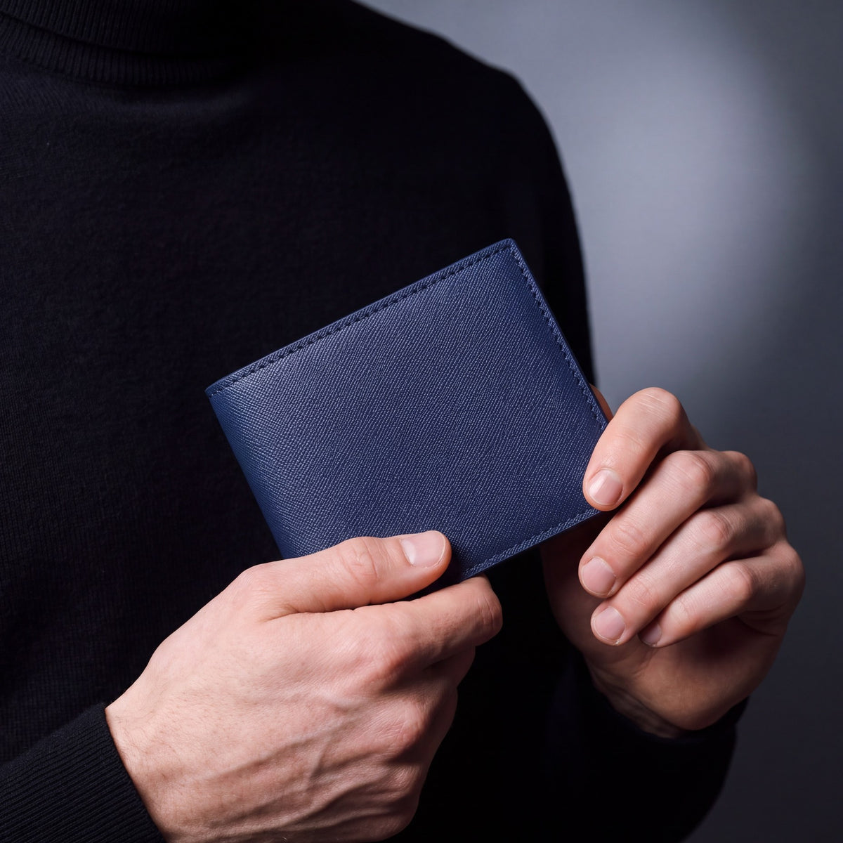 Close-up of hands holding a navy Saffiano leather bifold wallet by GENTCREATE