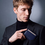 Man slipping a navy Saffiano leather card holder by GENTCREATE into a blazer chest pocket