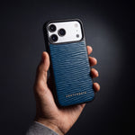 يد رجل تمسك جراب كحلي لهاتف iPhone 18 Pro Max من جلد عجل بنقش موجي بارز من GENTCREATE في استوديو مظلم