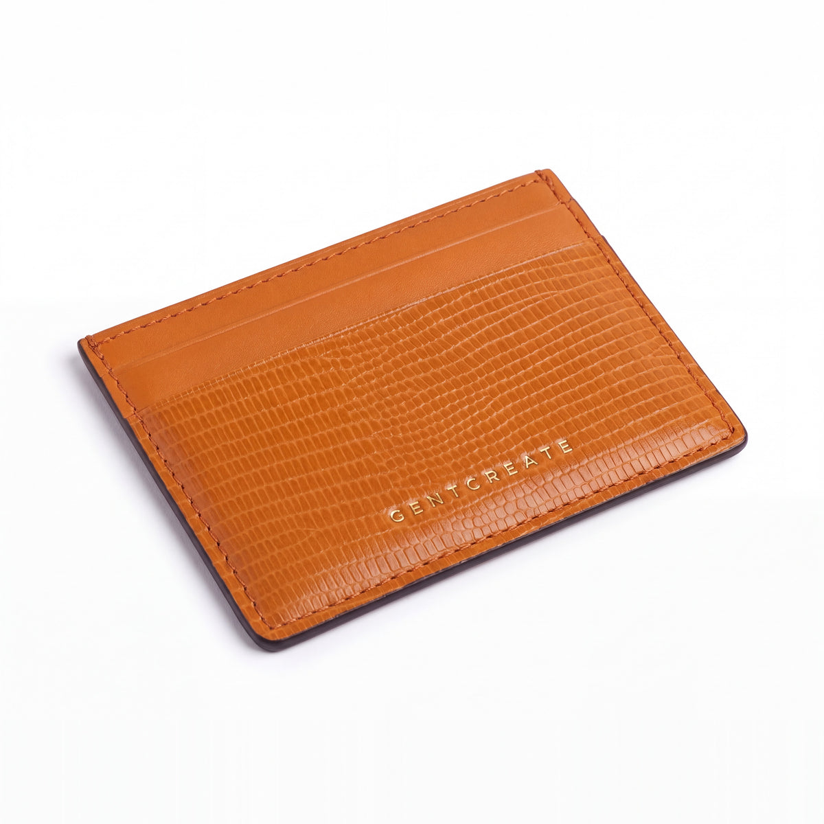 Orange lizard-embossed leather business card holder by GENTCREATE lying at an angle on white