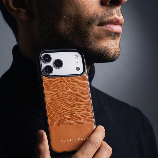 Man holding an orange lizard-embossed leather iPhone 18 Pro Max case by GENTCREATE against his jaw