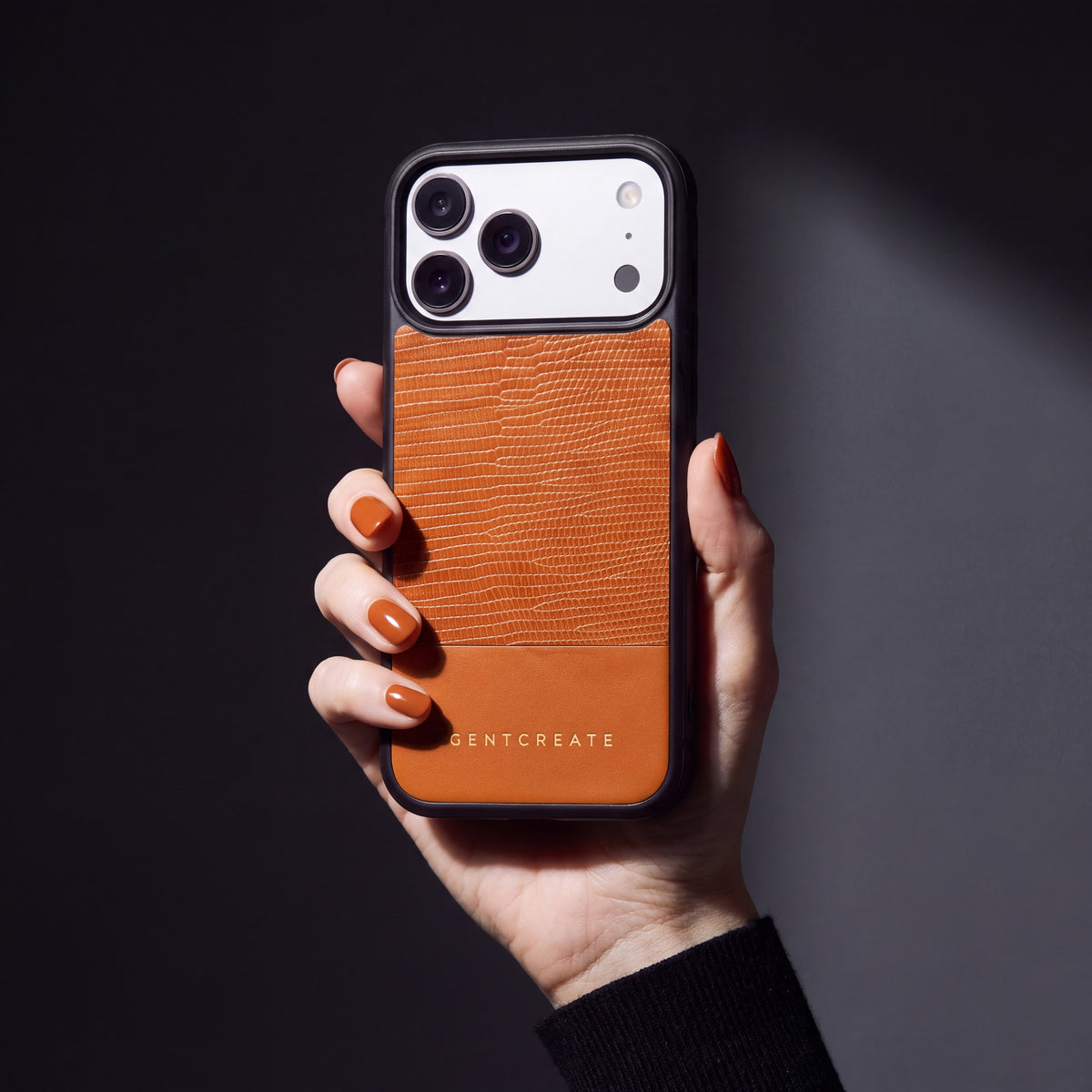 Hand mit orangebraunen Nägeln hält eine orangefarbene Hülle aus Kalbsleder mit Eidechsenprägung für iPhone 18 Pro Max von GENTCREATE