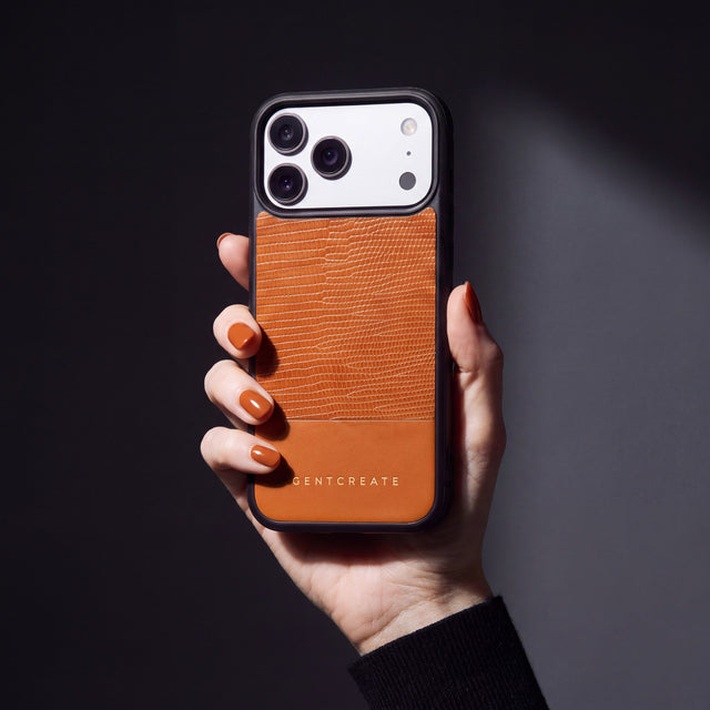 Hand with tan-orange nails holding an orange lizard-embossed calfskin iPhone 18 Pro Max case by GENTCREATE