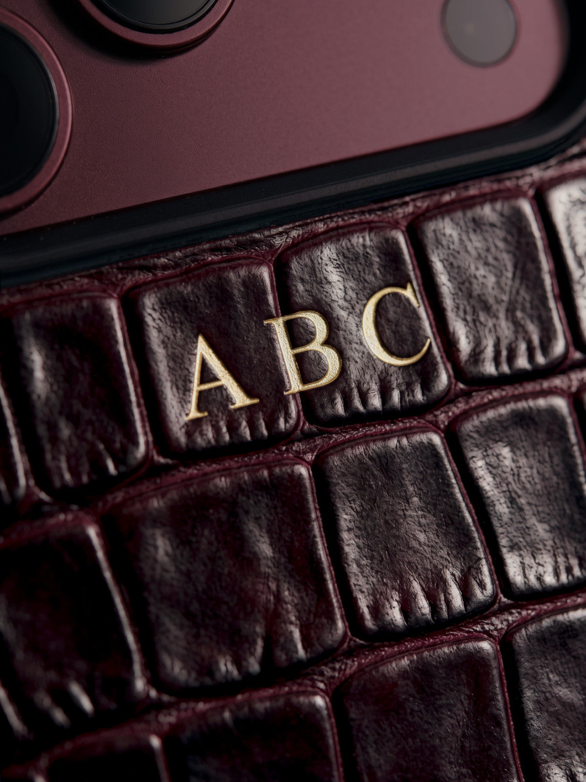 Visualization: the same close-up after a year of daily use: a deeper burgundy and softly burnished scales. The gold foil initials ABC are intact.