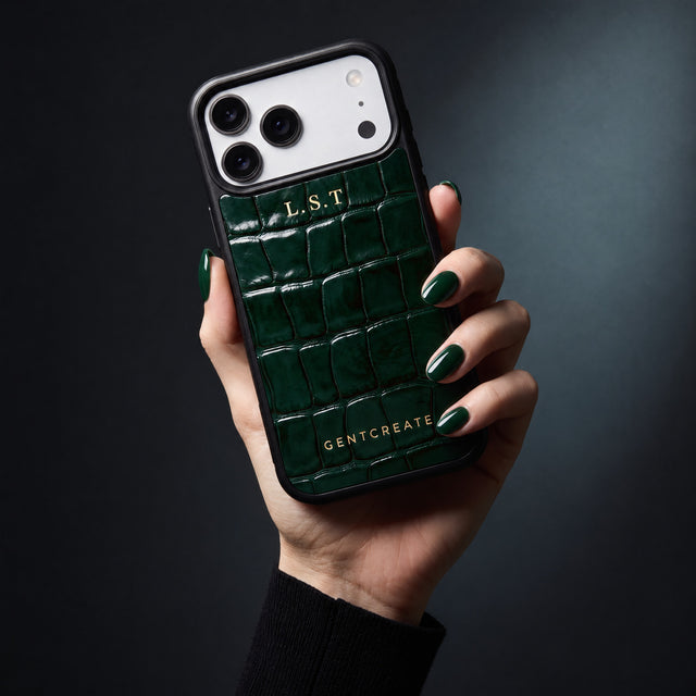 يد امرأة تمسك جرابًا أخضر لهاتف iPhone 18 Pro Max بنقش التمساح البارز من GENTCREATE يحمل الأحرف الأولى L.S.T بختم حراري ذهبي