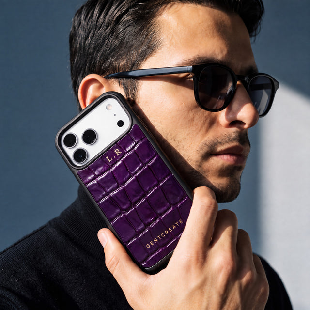 رجل يمسك إلى جانب وجهه جرابًا بلون الماجنتا لهاتف iPhone 18 Pro Max بنقش التمساح البارز من GENTCREATE يحمل الحرفين الأولين L.R بختم حراري ذهبي