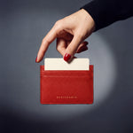 Hand holding a red pebble leather card holder by GENTCREATE, a card rising from the top slot