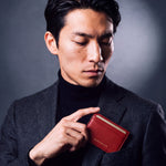 Man slipping a red pebble leather card holder by GENTCREATE into a blazer chest pocket