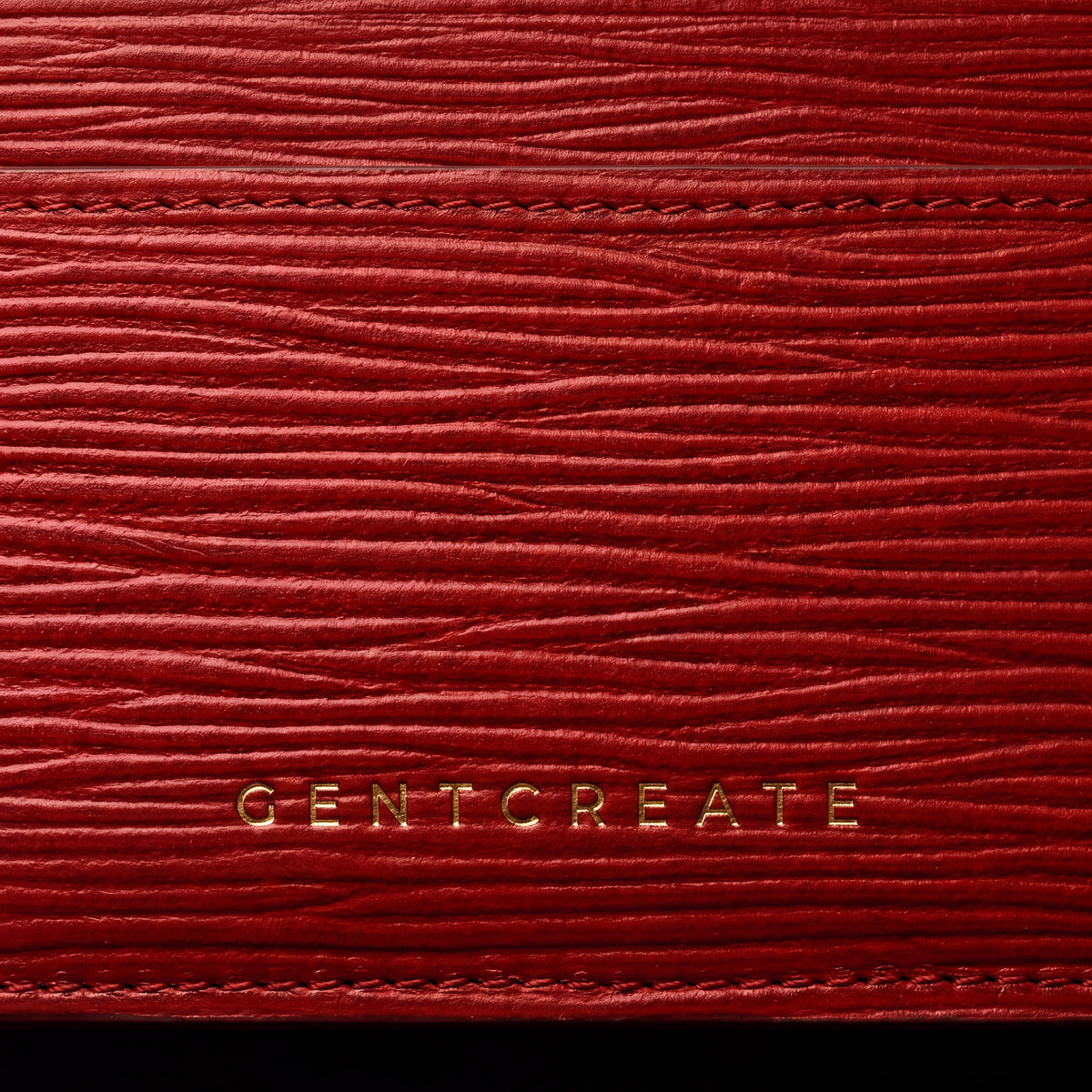 레드 웨이브 엠보싱 가죽 카드지갑에 금박으로 새긴 GENTCREATE 로고 클로즈업