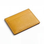 Yellow lizard-embossed leather business card holder by GENTCREATE lying at an angle on white