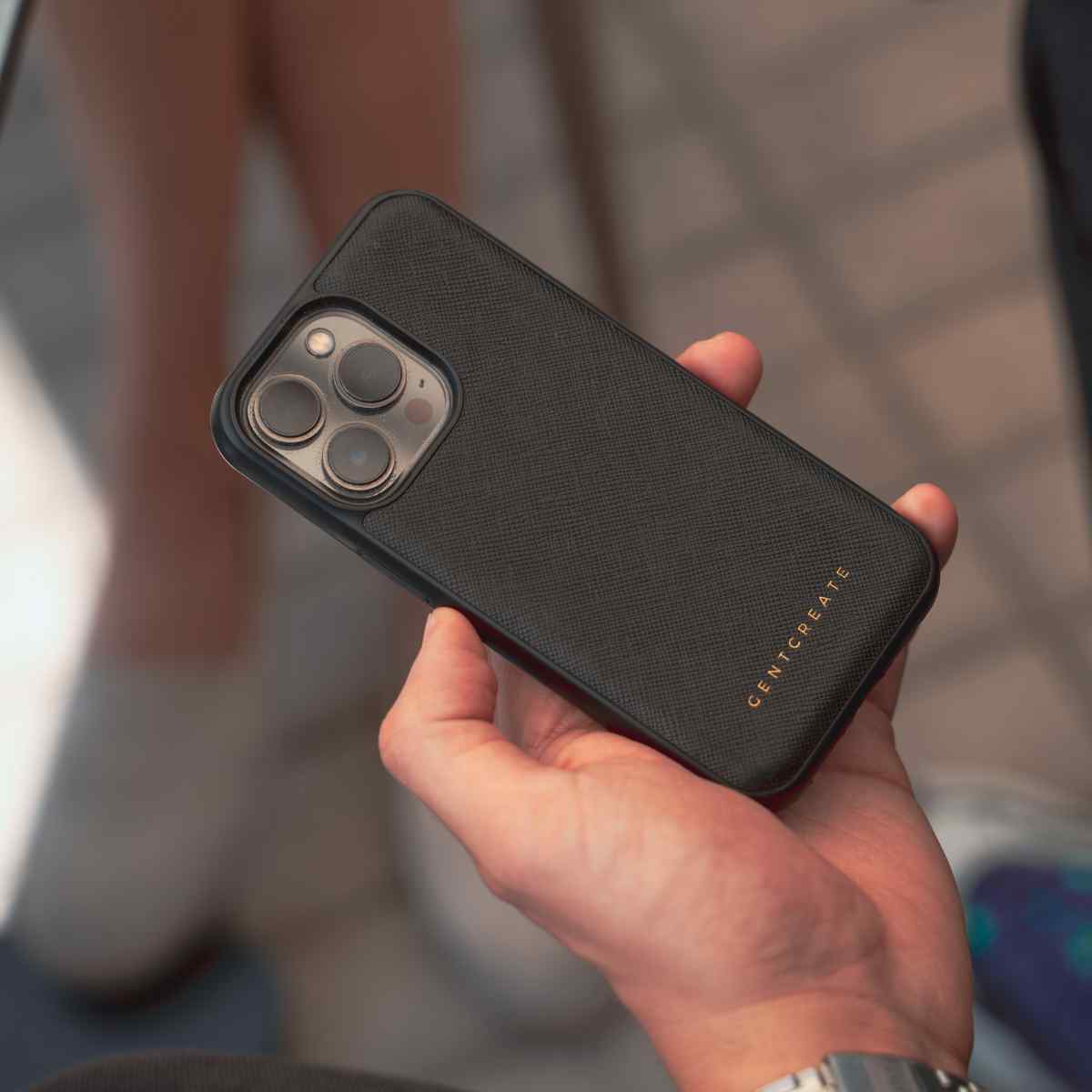 A man is holding an iPhone 13 mini in a Saffiano Black Leather Case by Gentcreate