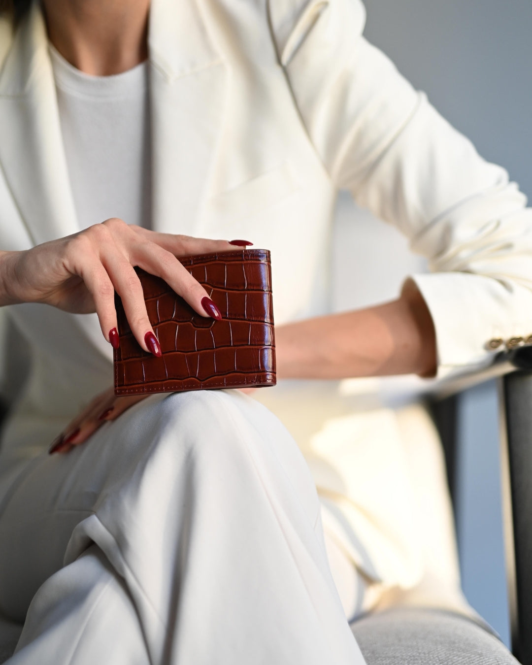 A burgundy crocodile-embossed GENTCREATE wallet in soft window light