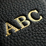 Super close up macro photograph of a handmade personalized custom initials monogram gold foil pebble leather iPhone 17 Pro Max Case by GENTCREATE