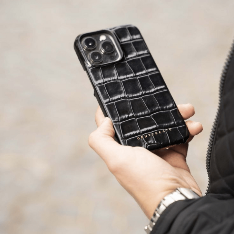 A man is holding a Black Glossy iPhone Leather Case in his hand
