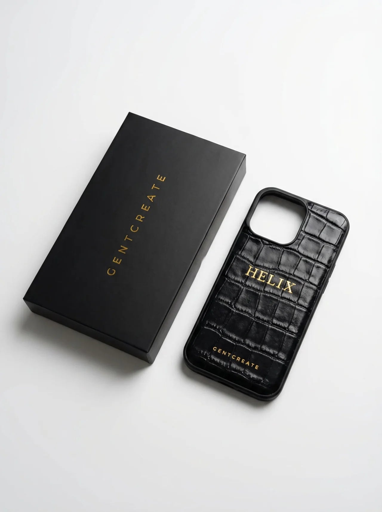 Capa para iPhone Helix em crocodilo preto com HELIX em folha dourada e um pequeno logótipo GENTCREATE, junto à sua caixa de apresentação GENTCREATE preta