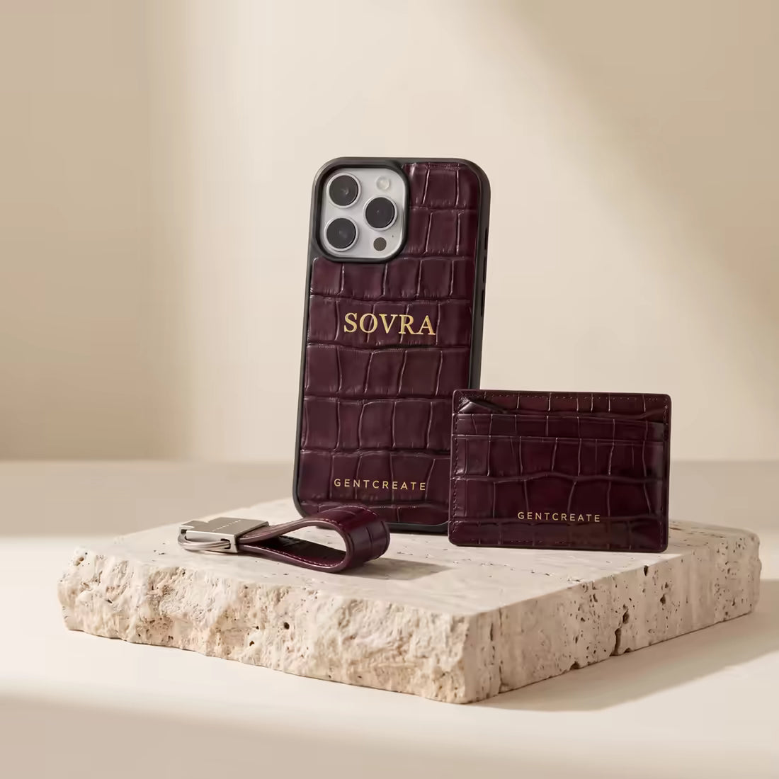 Capa para iPhone, porta-cartões e porta-chaves Sovra em crocodilo cor de sangue de boi, sobre travertino